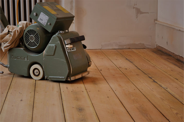 Parkettschleifmaschine auf geschliffenem Dielenboden.